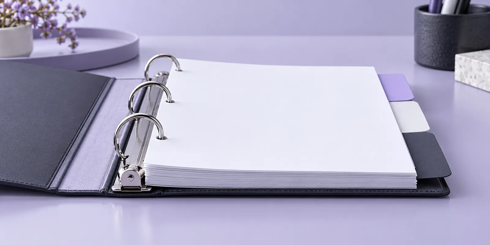 Open ring binder with blank pages and divider tabs on a lavender desk